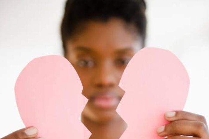 Woman holding a broken paper heart
