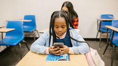 Girl sitting on her desk while using her smartphone [Image: RDNE Stock Project]