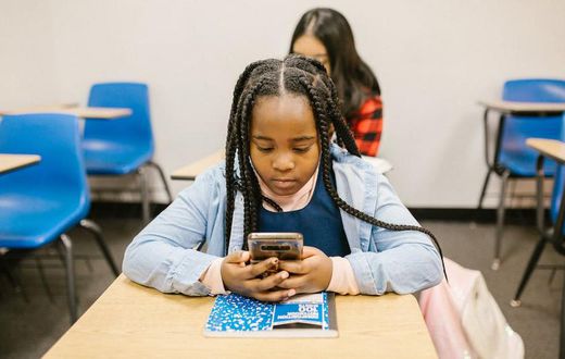 Girl sitting on her desk while using her smartphone [Image: RDNE Stock Project]