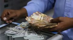 A person with Kenyan currency notes and U.S. dollars