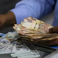 A person with Kenyan currency notes and U.S. dollars
