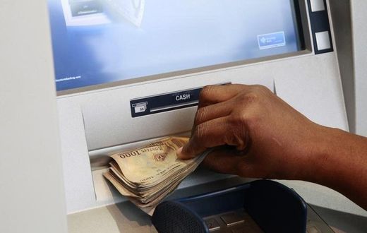 A woman takes Nigerian Naira from a bank's automated teller machine (ATM) in Ikeja district in the commercial capital Lagos November 12, 2014.