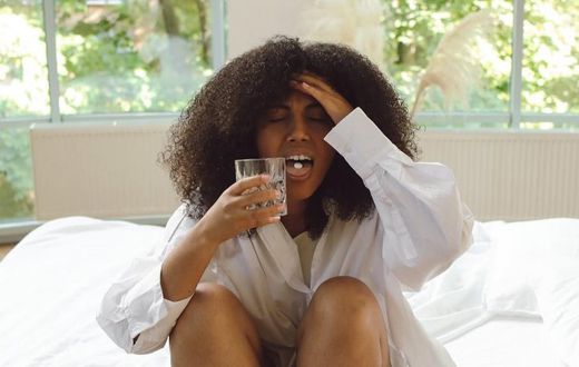 Woman in white long-sleeve shirt sitting on a bed [Image Credit: Polina Tankilevitch]