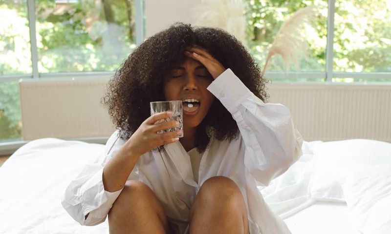 Woman in white long-sleeve shirt sitting on a bed [Image Credit: Polina Tankilevitch]