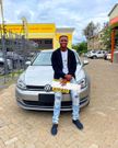 Kenyan TikTok sensation, dancer and digital content creator Only Lit Boy posing with his first car - a sleek silver-grey Volkswagen Golf TSI