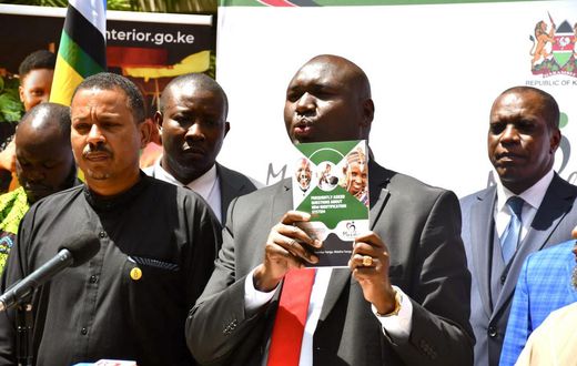 Immigration and Citizen Services PS Julius Bitok displays a copy of a booklet on Frequently Asked Questions (FAQs) on Digital ID to the media at the Nairobi Serena Hotel. Looking on is Amnesty International Kenya Executive Director Irungu Houghton