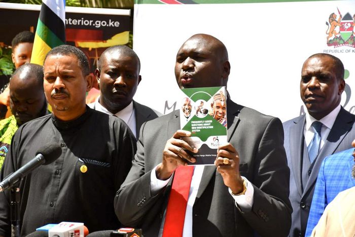 Immigration and Citizen Services PS Julius Bitok displays a copy of a booklet on Frequently Asked Questions (FAQs) on Digital ID to the media at the Nairobi Serena Hotel. Looking on is Amnesty International Kenya Executive Director Irungu Houghton