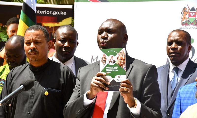 Immigration and Citizen Services PS Julius Bitok displays a copy of a booklet on Frequently Asked Questions (FAQs) on Digital ID to the media at the Nairobi Serena Hotel. Looking on is Amnesty International Kenya Executive Director Irungu Houghton