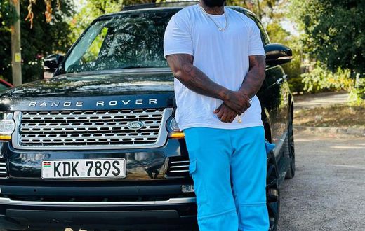 Khaligraph Jones posing with a Range Rover