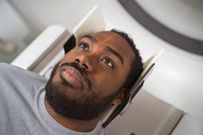 Photo of a male patient undergoing MRI scan in medical examination room