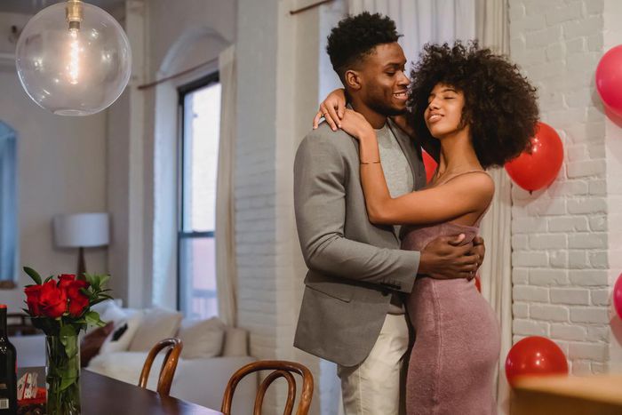 Couple dancing while hugging in a room near the table