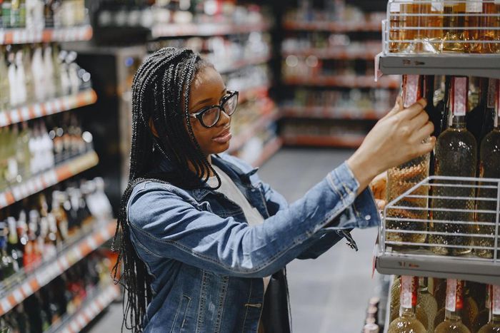 Woman shopping for wine in grocery store [Photo: Gustavo Fring]