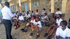 A teacher with students during a class discussion held outdoors