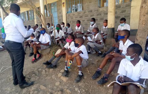 A teacher with students during a class discussion held outdoors
