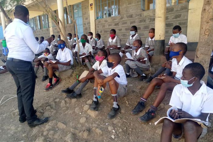A teacher with students during a class discussion held outdoors