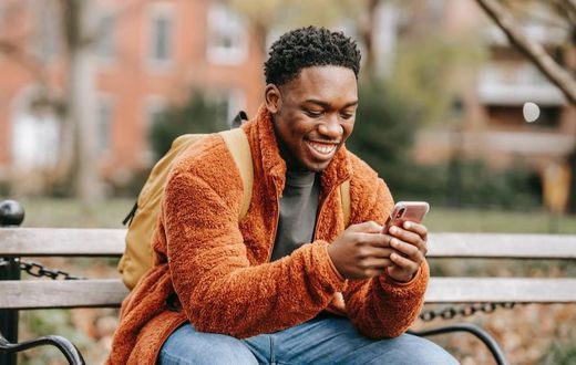 Delightful man surfing modern cellphone in a city park [Photo: Keira Burton]