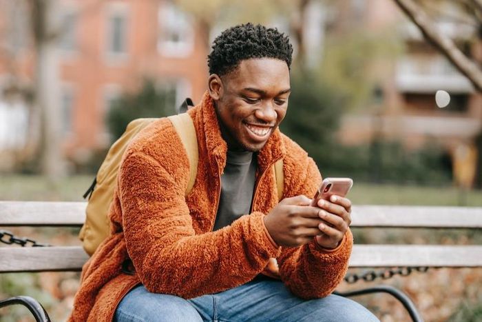 Delightful man surfing modern cellphone in a city park [Photo: Keira Burton]